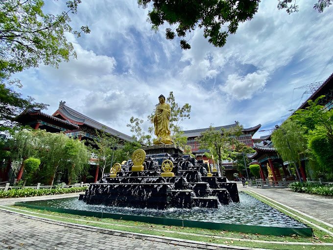 Golden Buddha water feature framed by traditional architecture at Nirvana Shah Alam