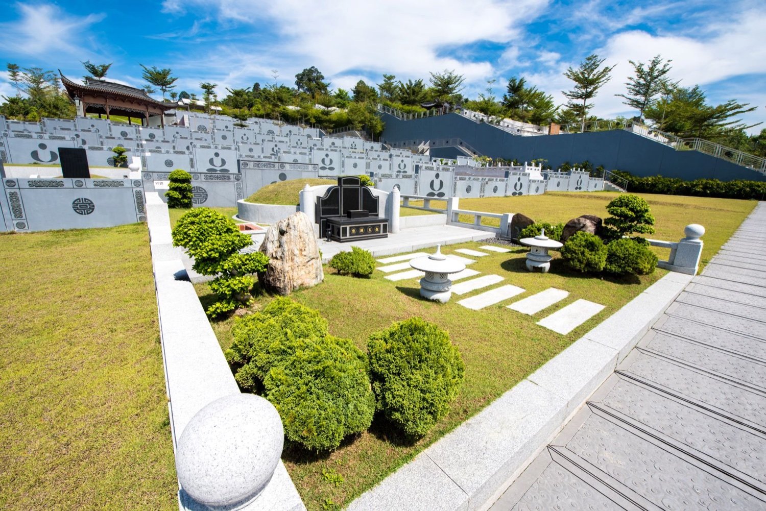 Landscaped burial plot with ornamental stonework and garden planting
