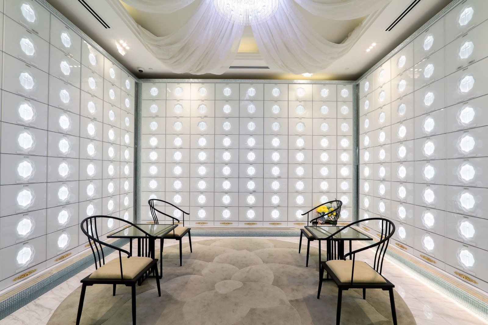 Bright Christian columbarium visitor room with softly illuminated niche walls and family seating