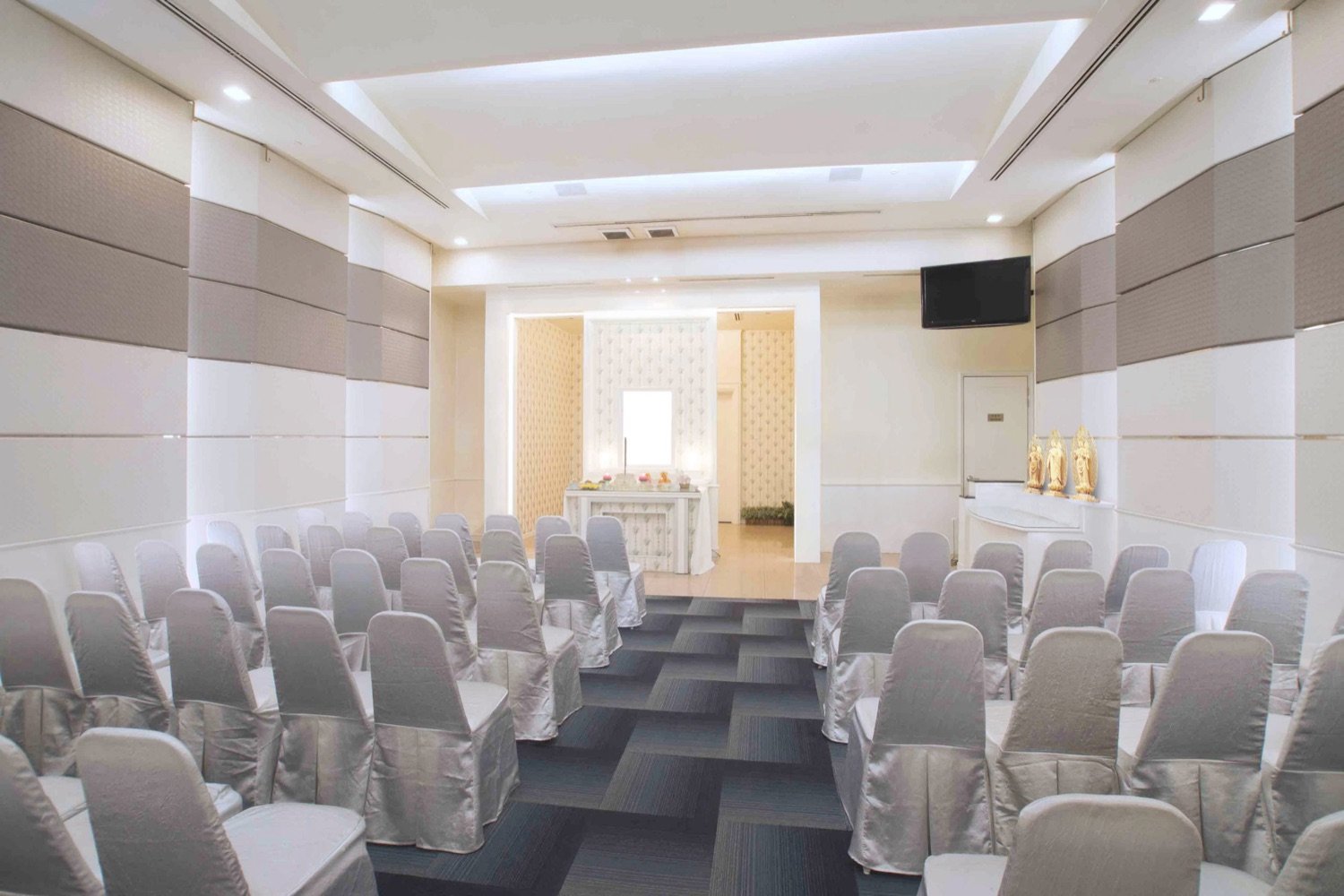 Buddhist memorial parlour with rows of guest seating and a faith-specific altar setting