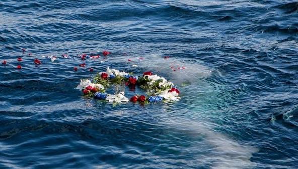 An illustrative floral wreath floating on the sea after a memorial farewell
